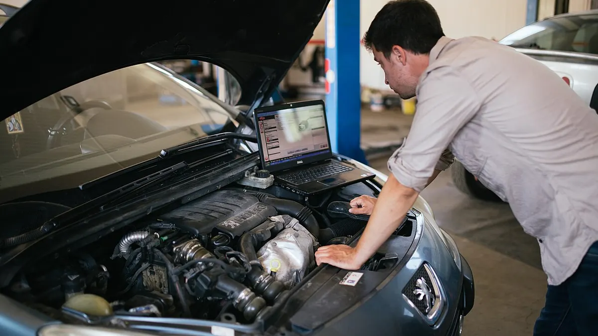 An automotive technician diagnosing a vehicle in a repair shop