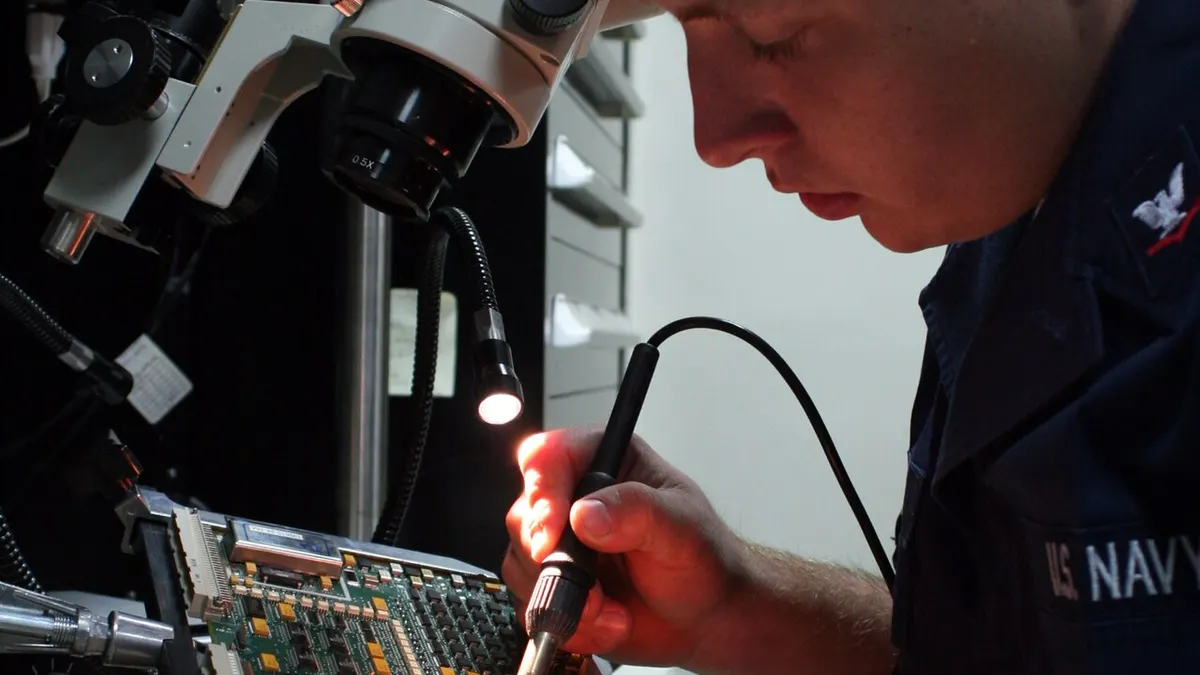 An electronics technician performing detailed hands-on work